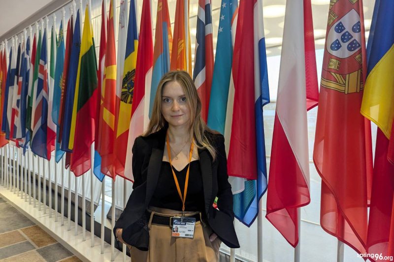 девушка в черной блузке на фоне флагов 